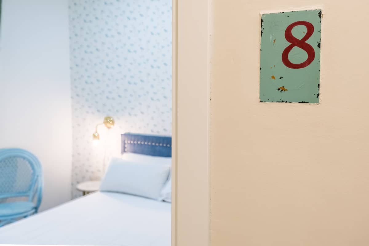 Una habitación con una cama, una silla azul y una pared con el letrero del número 8.