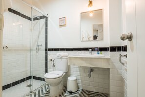 Un baño con ducha acristalada, inodoro, lavabo y espejo.