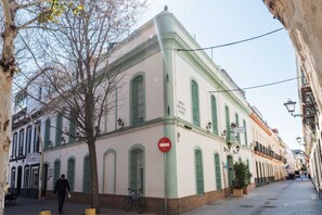Un edificio histórico con ventanas arqueadas y un cartel de 'prohibido el paso', situado en una calle estrecha peatonal.