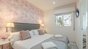 Habitación de hotel con una cama grande, dos mesitas de noche, un televisor y una ventana con vistas.