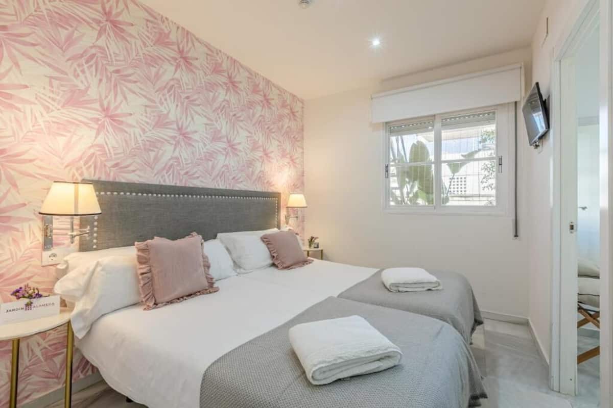 Habitación de hotel con una cama grande, dos mesitas de noche, un televisor y una ventana con vistas.