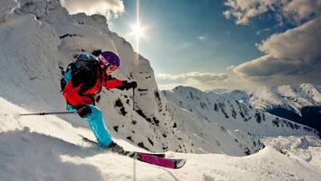 A skier on a snowy mountain slope with a clear sky and distant mountains.