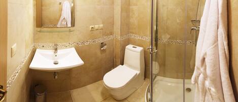 Un baño con lavabo, inodoro y ducha con mampara de vidrio.