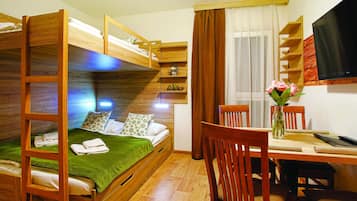 Habitación con literas, escritorio, sillas, televisor y ventana con cortinas.