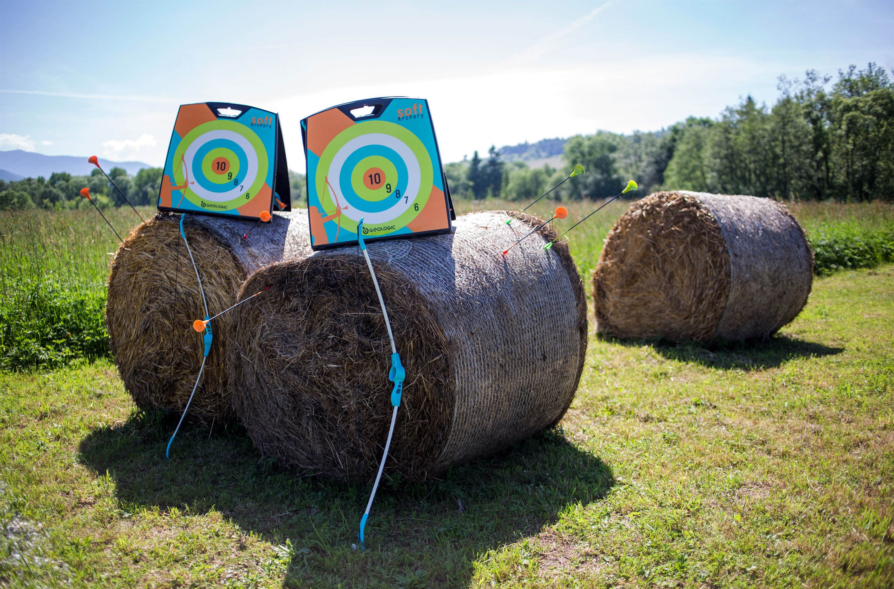 Three hay bales with target boards on them in an open field.