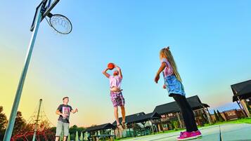 A basketball court with a hoop, a net, and a clear sky.