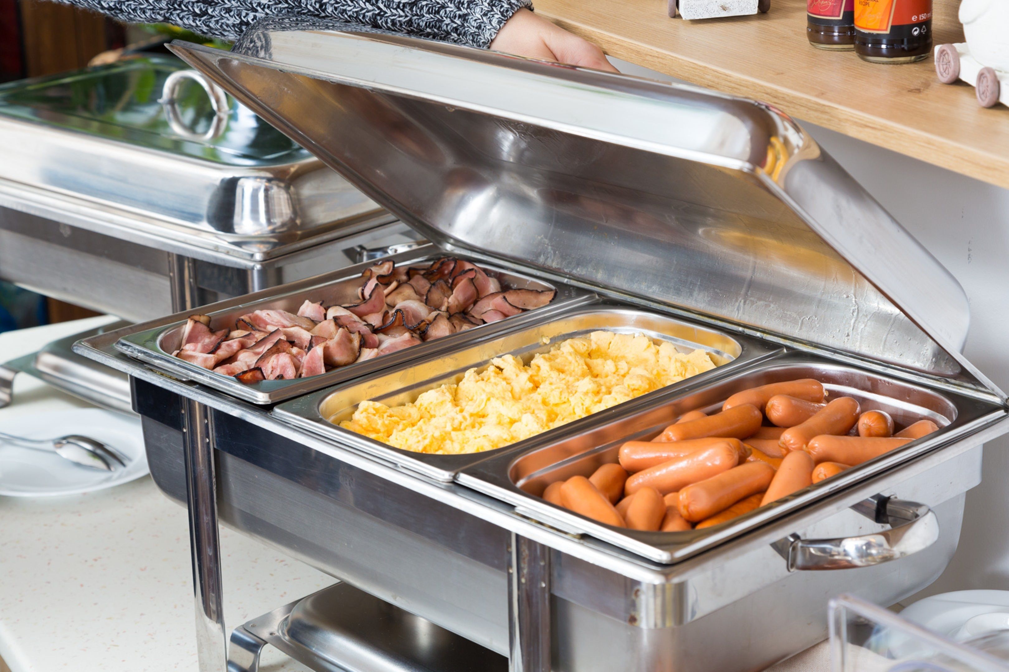 Ein reichhaltiges Buffet mit verschiedenen Speisen, darunter Wurst, Rührei und weitere Gerichte.