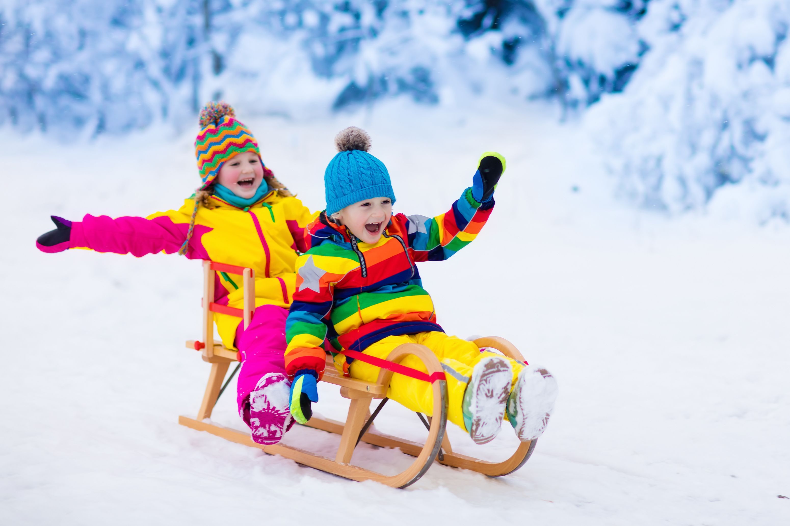 Duas crianças escorregando na neve.