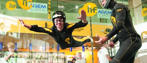 A person in a black and yellow suit performing a stunt in front of a glass window with the logo "hf AGEM DATA".