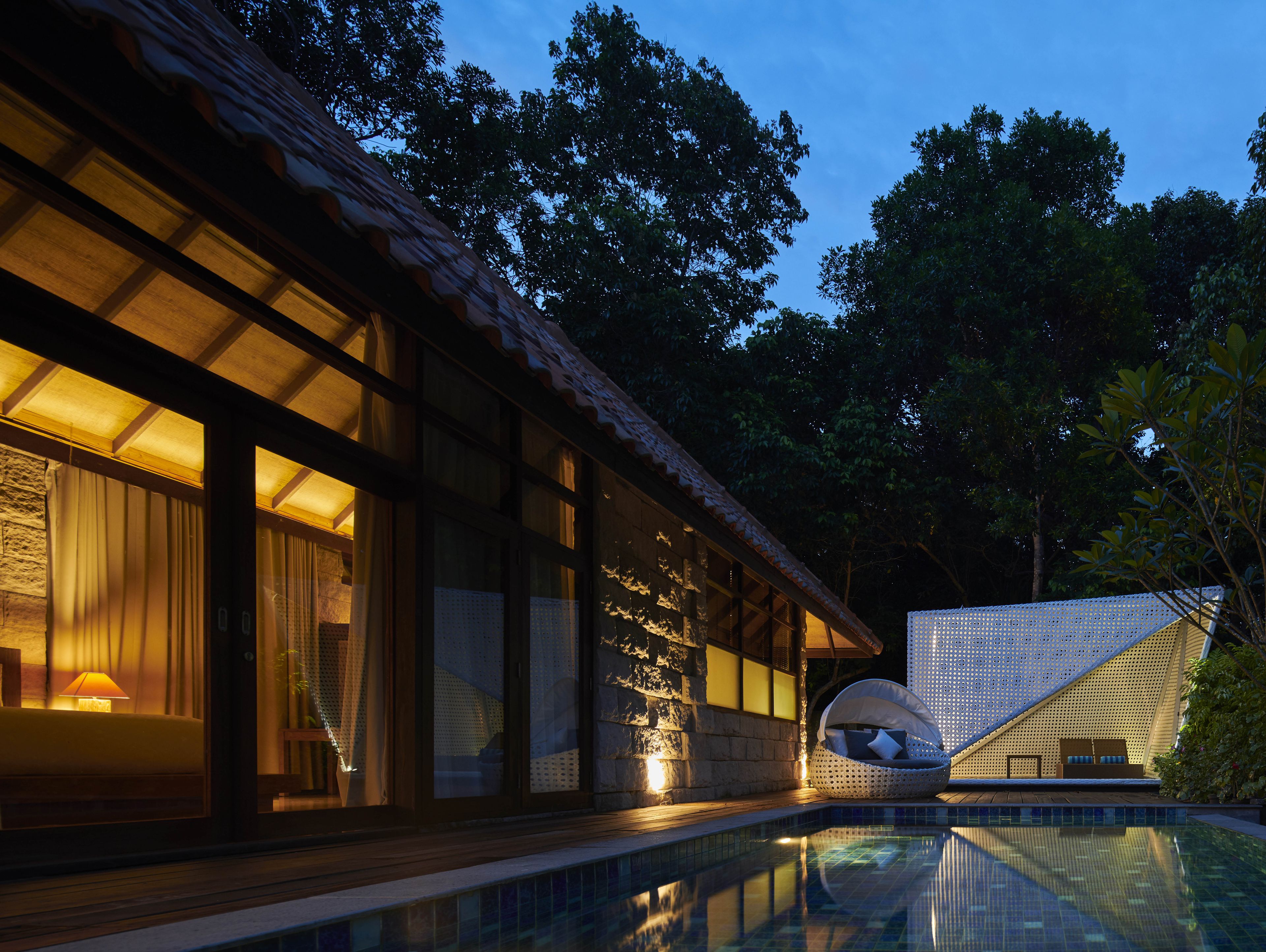 A modern building with a swimming pool, large windows, and a covered seating area.