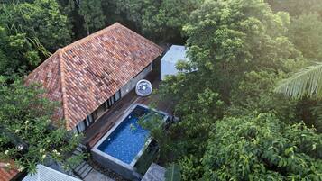 Piscina en la azotea con techo de tejas, rodeada de abundante vegetación.
