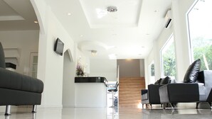 Un intérieur moderne avec un comptoir d’accueil élégant, un escalier et un espace détente doté de canapés en cuir.