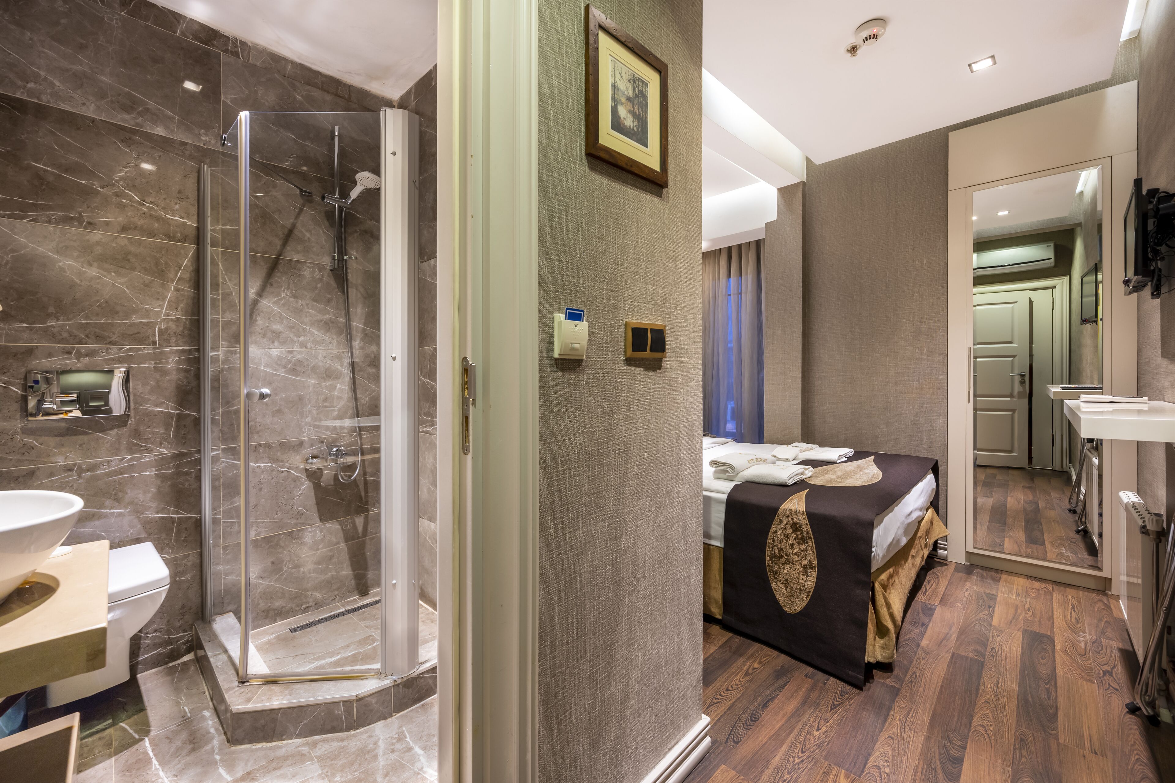 Une salle de bain moderne dotée d’une douche à parois de verre, de toilettes et d’un lavabo.