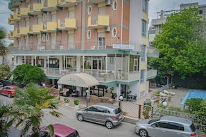 Een hotel met meerdere verdiepingen, balkons, terrasjes en een zwembad.
