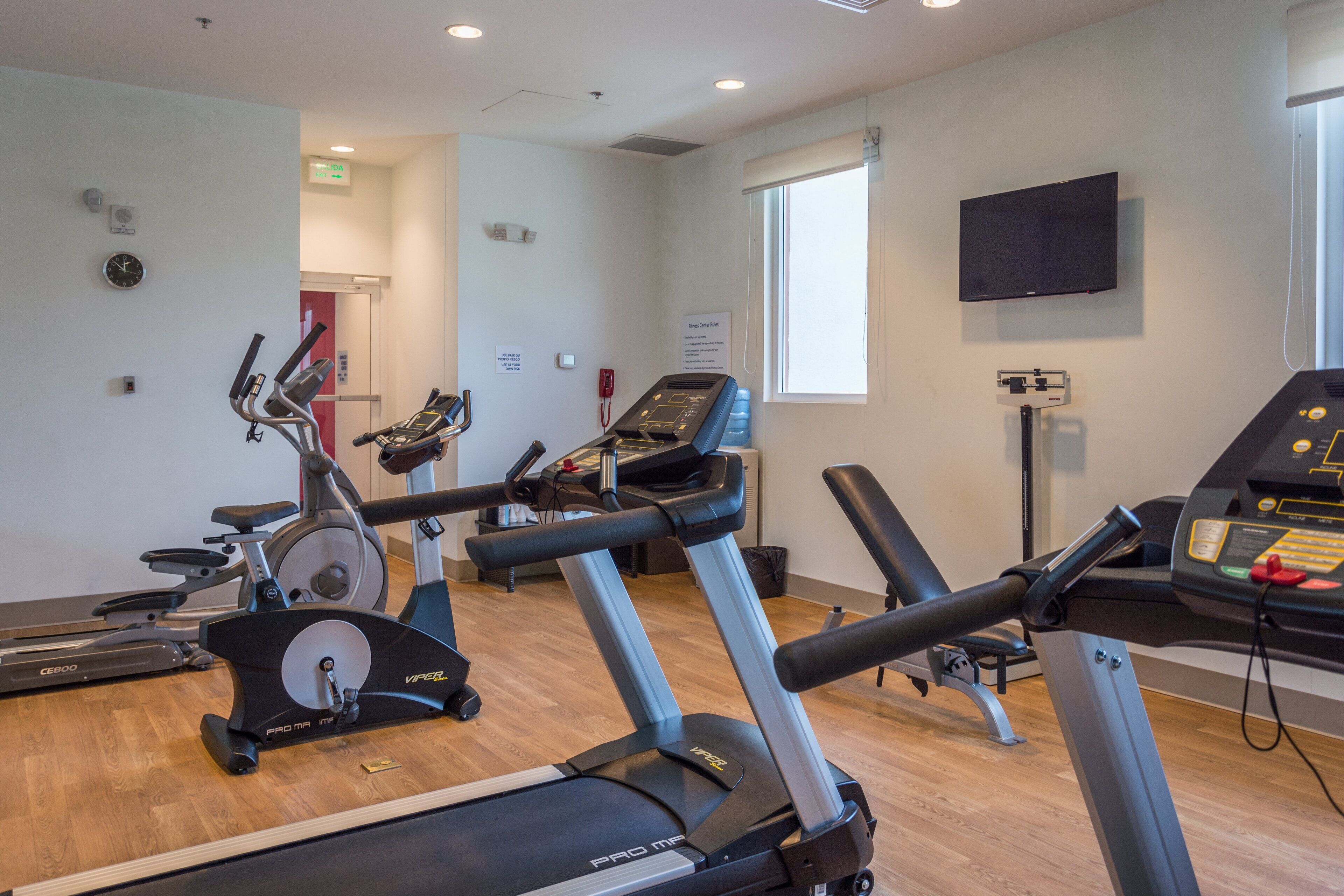 A gym with treadmills, stationary bikes, and a weight bench.