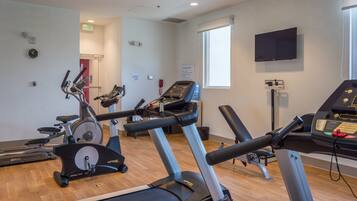 A gym with treadmills, stationary bikes, and a weight bench.