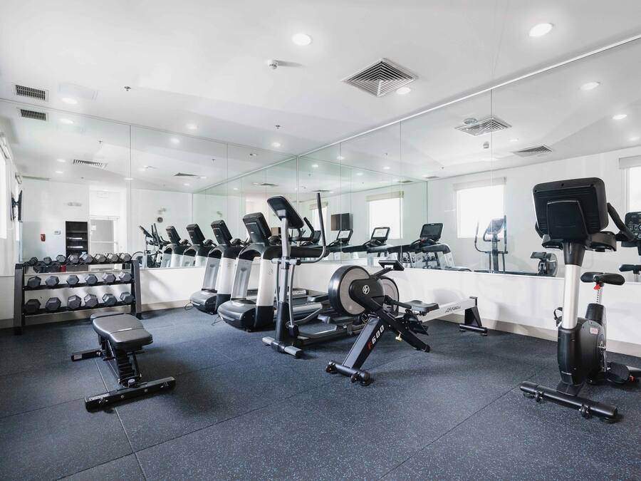 Ett gym med olika typer av träningsutrustning, inklusive löpband, motionscyklar och styrketräningsmaskiner.