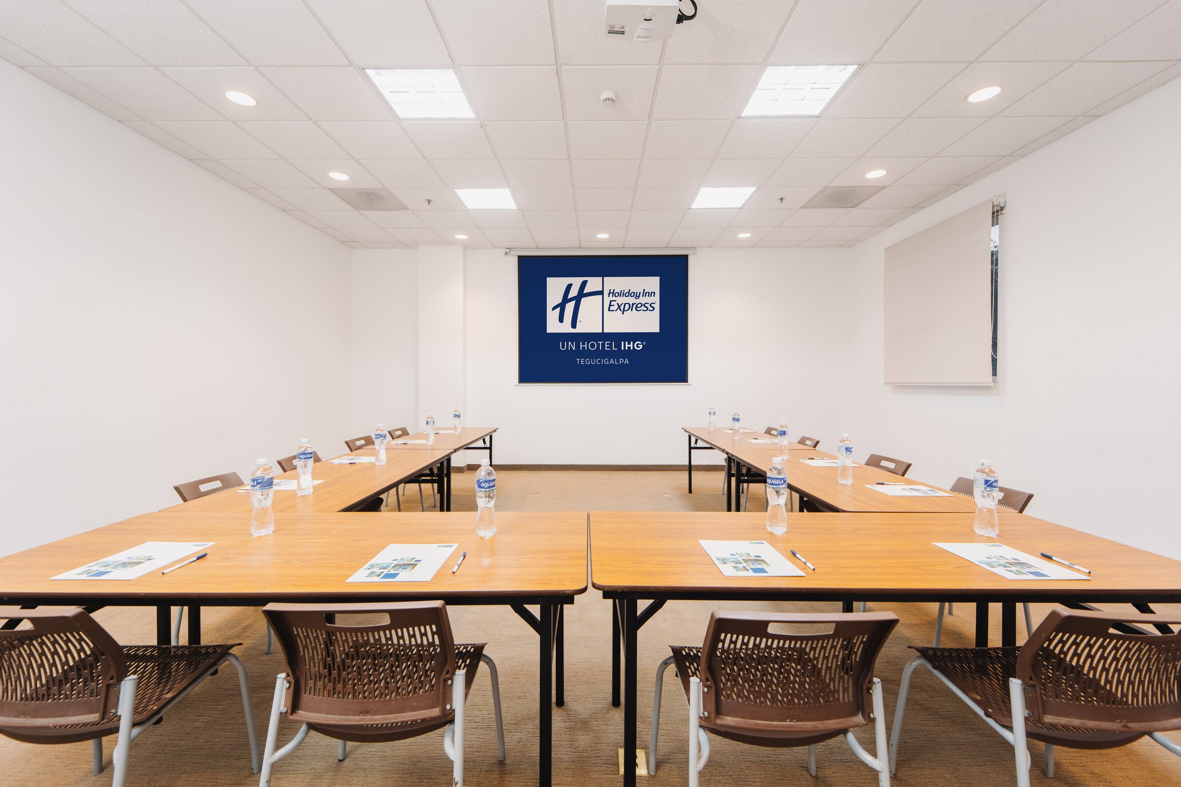 A conference room with a long table, chairs, and a banner displaying the Holiday Inn Express logo.