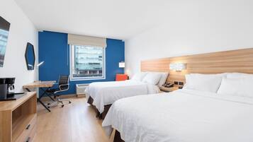 A hotel room with two beds, a desk with a chair, a lamp, and a window with blinds.