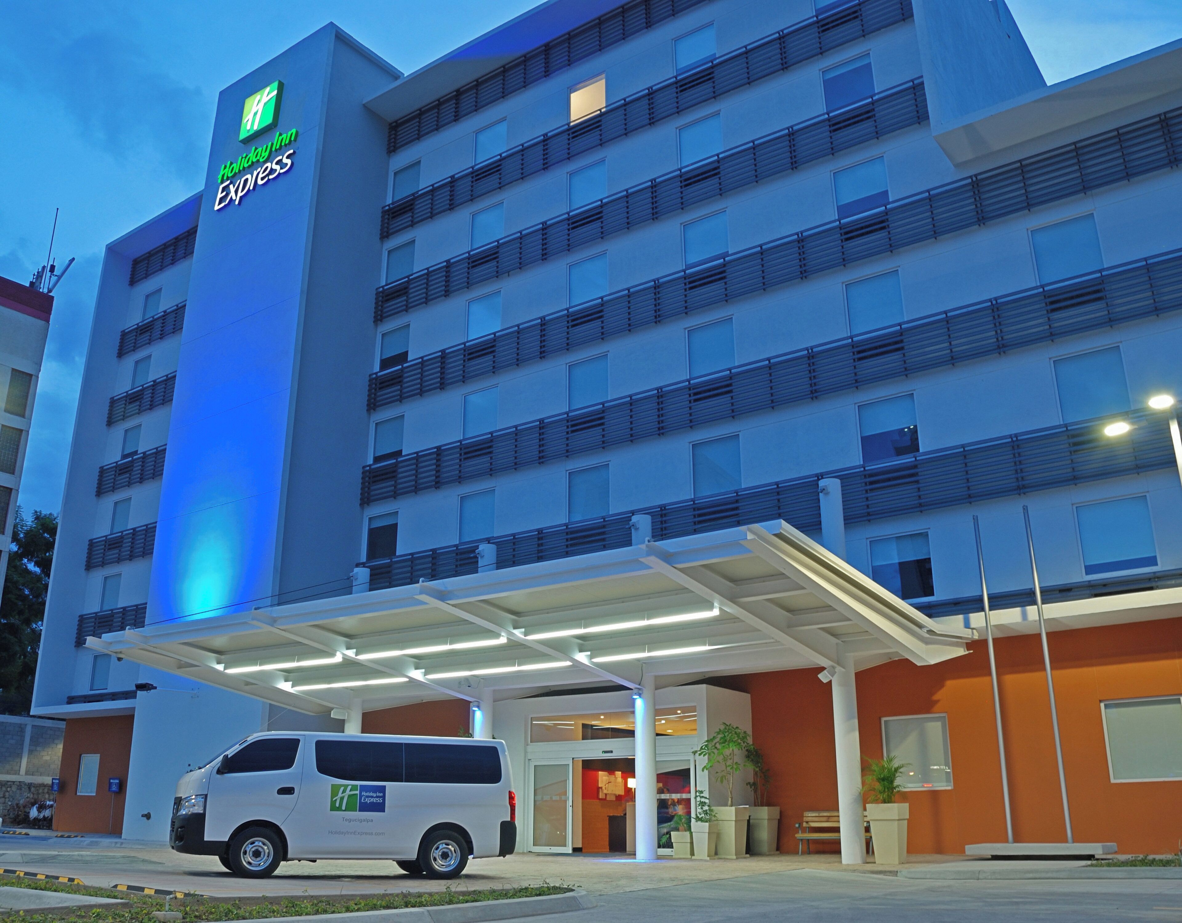 Um hotel Holiday Inn Express com fachada branca, várias varandas e área de entrada coberta.