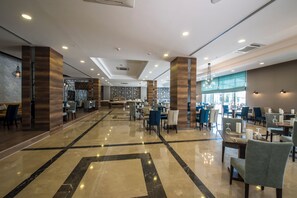 A spacious hotel lobby with a modern design, featuring a central seating area, multiple dining tables, and a large window providing natural light. - Premier Inn Sakarya (Erenler)