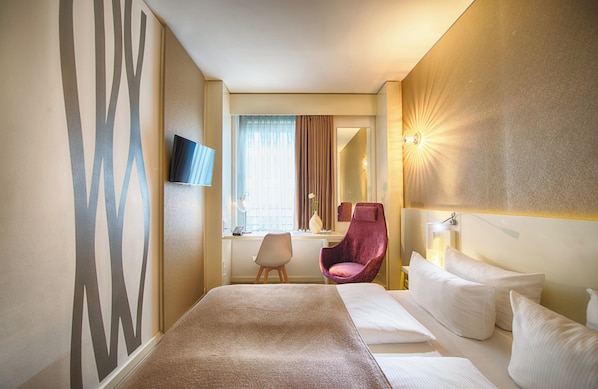 A hotel room with a bed, a desk, a chair, a TV, and a mirror. - Leonardo Hotel Berlin Mitte (Berlin)