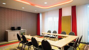 Un salón de conferencias con una larga mesa, varias sillas, una pizarra y un sistema de sonido.
