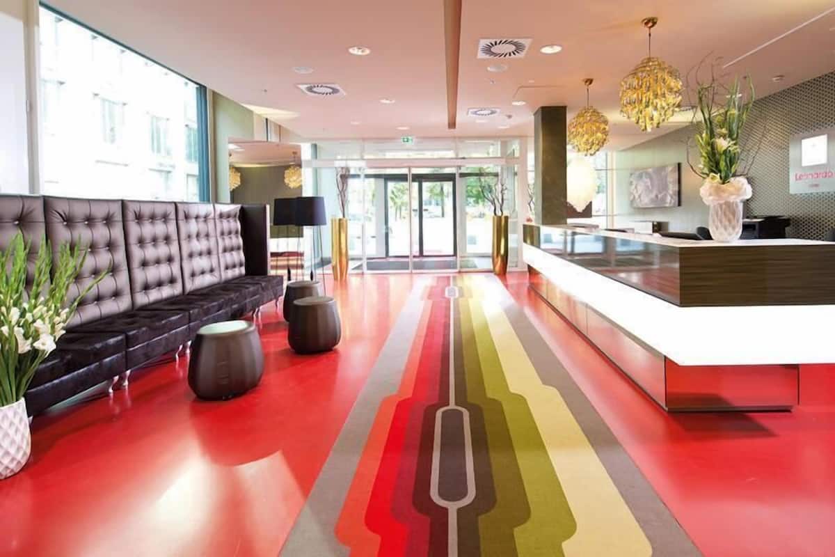 Un moderno hall con un sofá capitonado, una recepción y una alfombra a rayas coloridas.