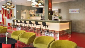 Zona de bar moderna con una barra larga, varios taburetes y una gran variedad de botellas y vasos.