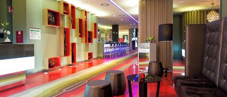Un moderno vestíbulo de hotel con alfombra roja, zona de estar y mostrador de recepción.