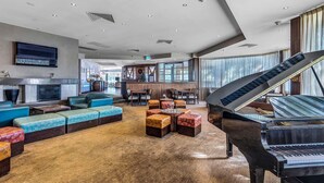 A spacious lobby with a grand piano, comfortable seating, a fireplace, and a television. - The Sebel Swan Valley The Vines (The Vines)
