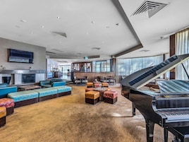 Un lobby espacioso con un piano de cola, asientos cómodos, chimenea y televisión.