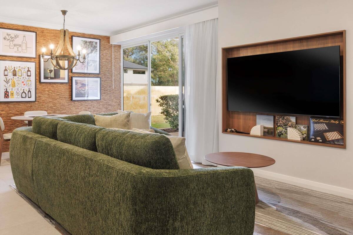 Ein modernes Wohnzimmer mit einem Ecksofa, einem Flachbildfernseher und einer Kronleuchter.