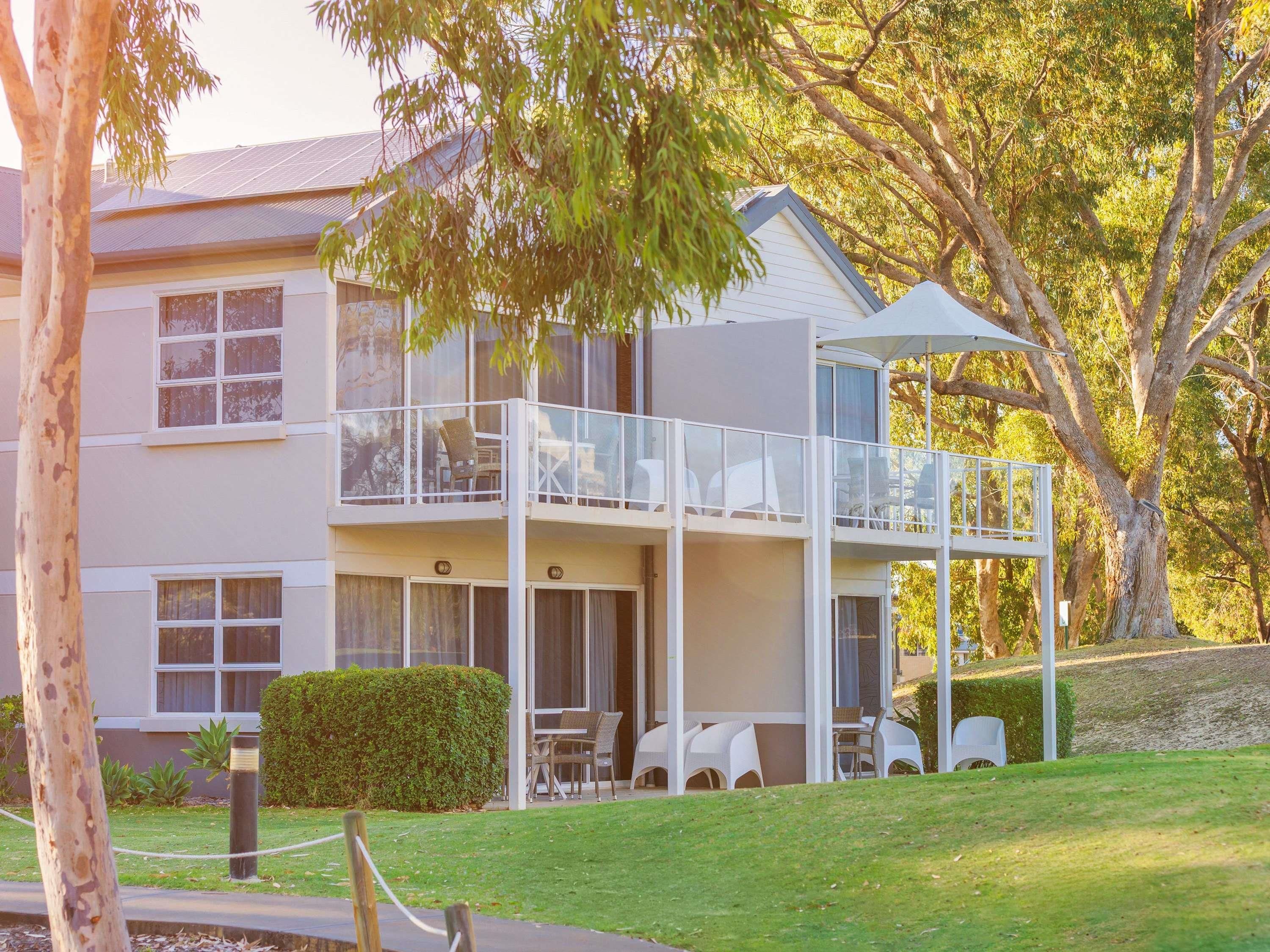 A two-story building with a balcony, outdoor seating, and a covered area.