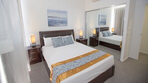 Een hotelkamer met een groot bed, een nachtkastje, een spiegel en een schilderij aan de muur.