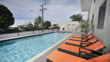 Una piscina al aire libre, sillones reclinables de piscina