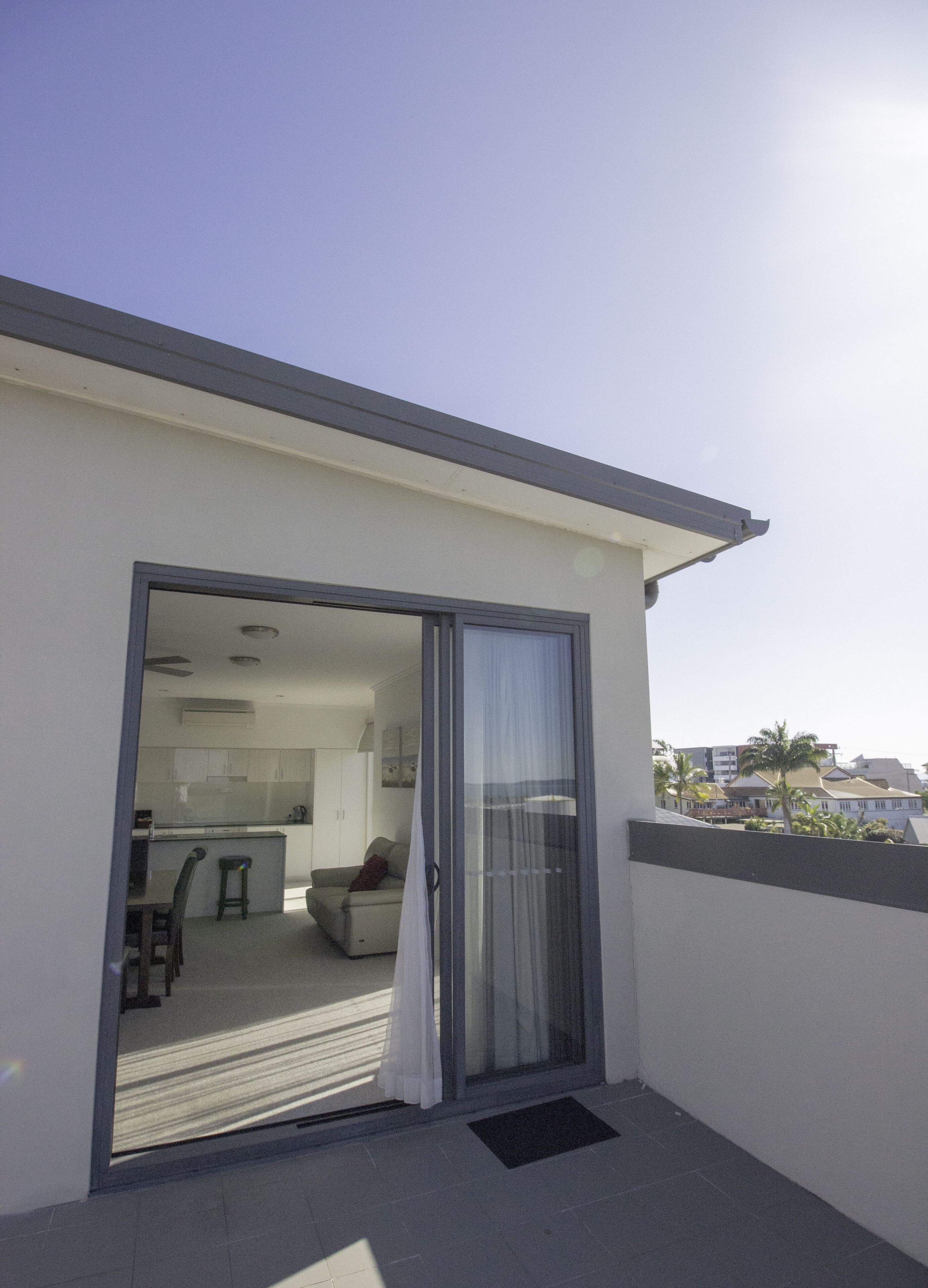 A modern balcony with a sliding glass door leading to a compact kitchen and living area.