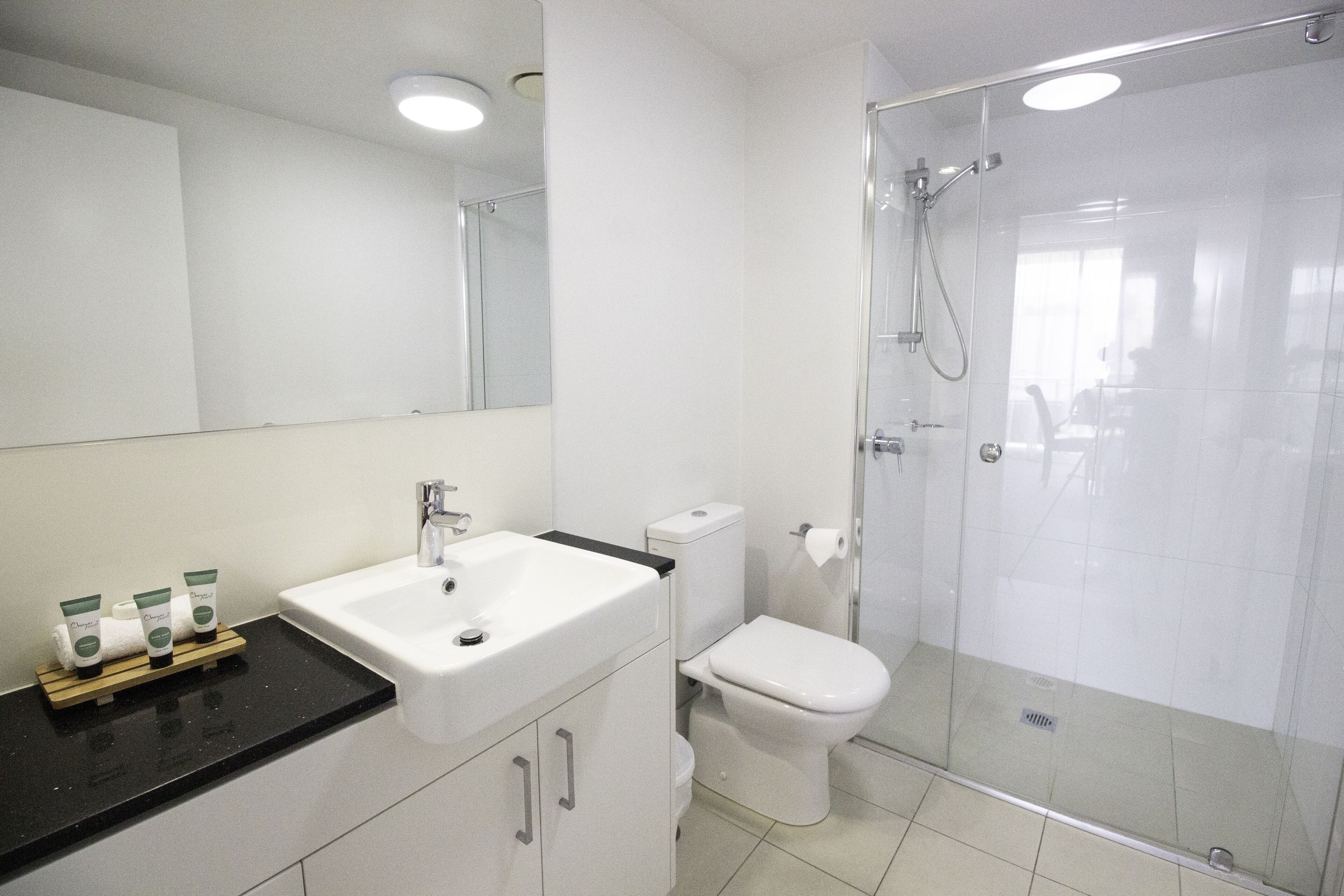 A modern bathroom with a white sink, toilet, and glass-enclosed shower.