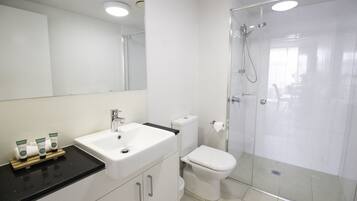 A modern bathroom with a white sink, toilet, and glass-enclosed shower.