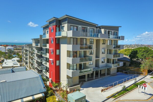 A multi-story residential building with balconies, a parking area, and a view of the sea. - Gladstone Central Plaza (Gladstone)