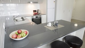 Een moderne keuken met een groot eiland, roestvrijstalen apparatuur en een schaal appels.
