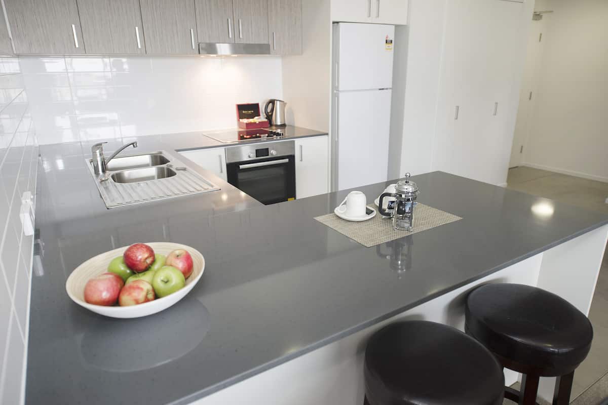 Een moderne keuken met een groot eiland, roestvrijstalen apparatuur en een schaal appels.