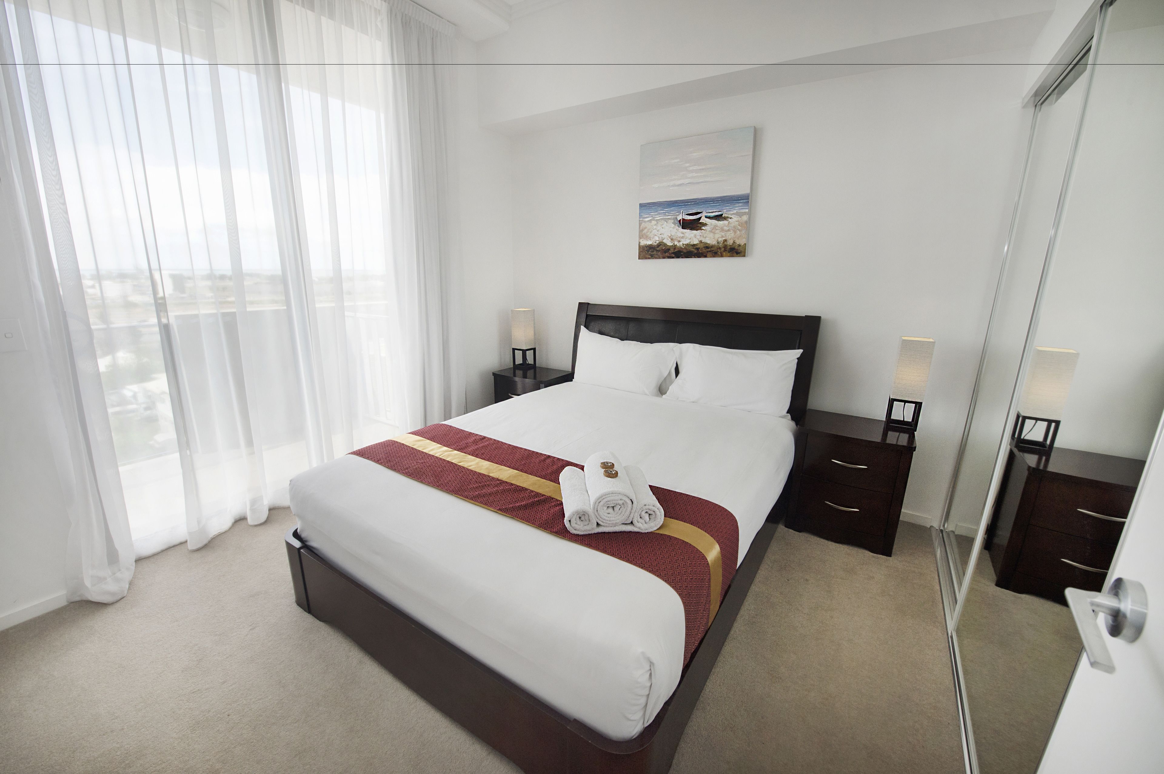 Una camera d'albergo con un letto grande, un comodino con una lampada, un quadro appeso al muro e una vista dalla finestra.