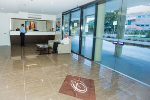 A reception area with a receptionist, a waiting area with a seated guest, and a reception desk. - Gladstone Central Plaza (Gladstone)
