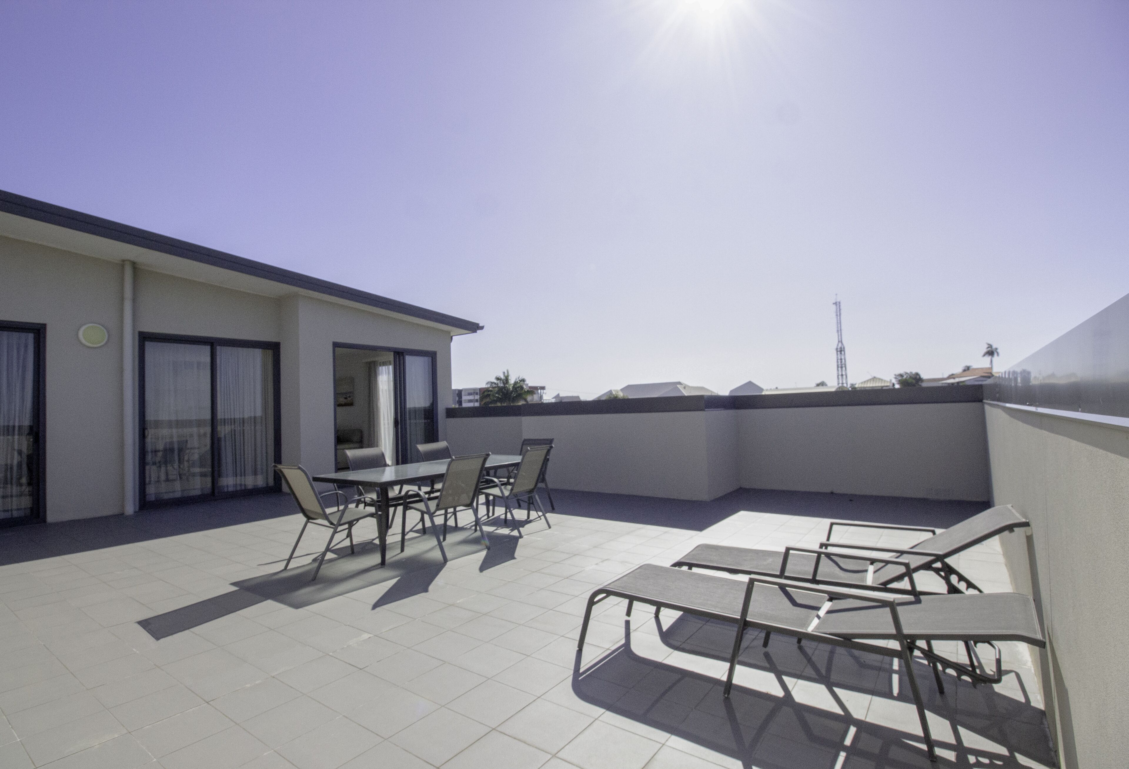 Una terraza en la azotea con zona de comedor, mesas y sillas, y vistas al horizonte de la ciudad.