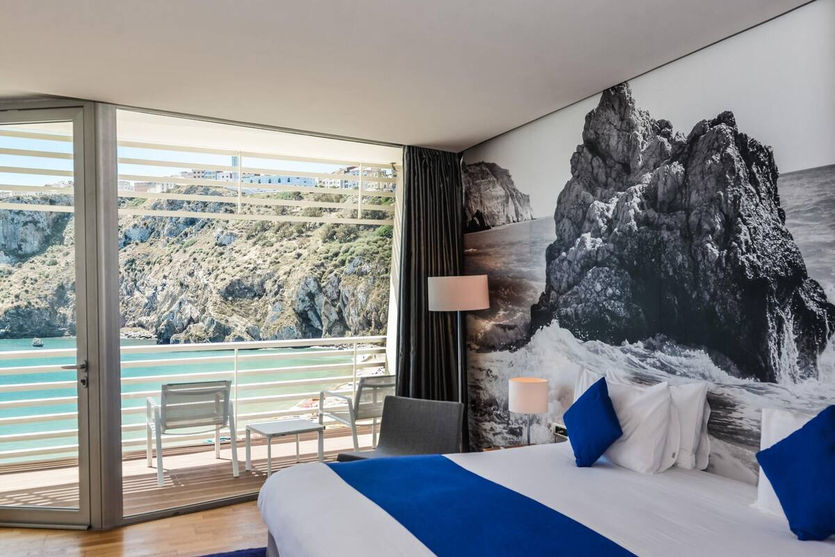 A bedroom with a large bed, a view of the sea, and a balcony.