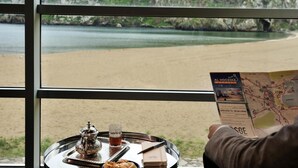 A table with a tray containing a teapot, a glass of tea, and pastries, with a map of Al Hoceima city in the foreground. - Mercure Quemado Resort (Al Hoceima)