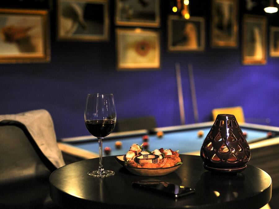 Une table de billard avec un saladier rempli de nourriture et un verre de vin posés sur une table.
