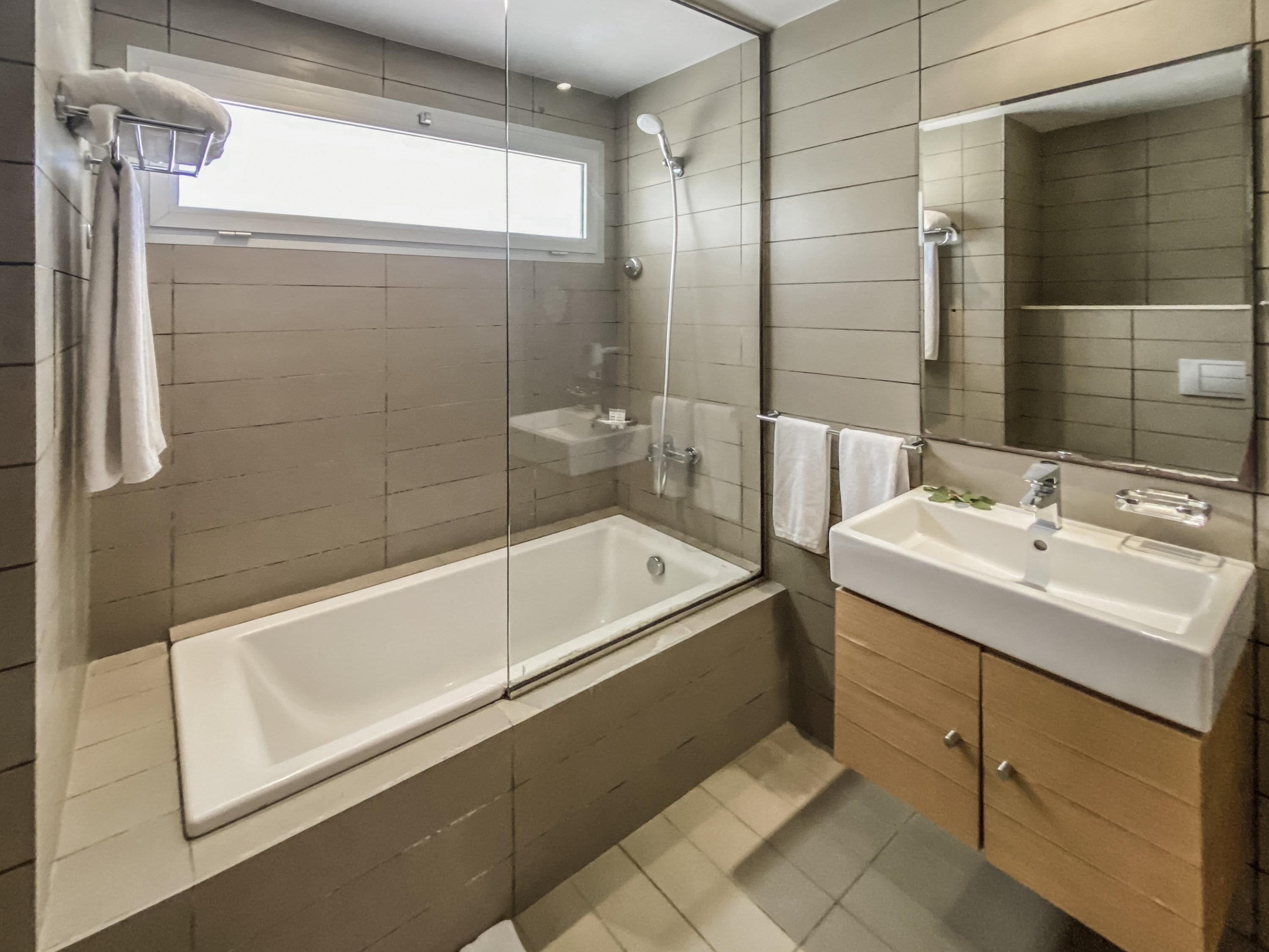 Ein modernes Badezimmer mit einer gläsernen Duschkabine, einer freistehenden Badewanne und einem Waschtisch.
