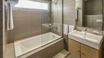 Ein modernes Badezimmer mit einer gläsernen Duschkabine, einer freistehenden Badewanne und einem Waschtisch.